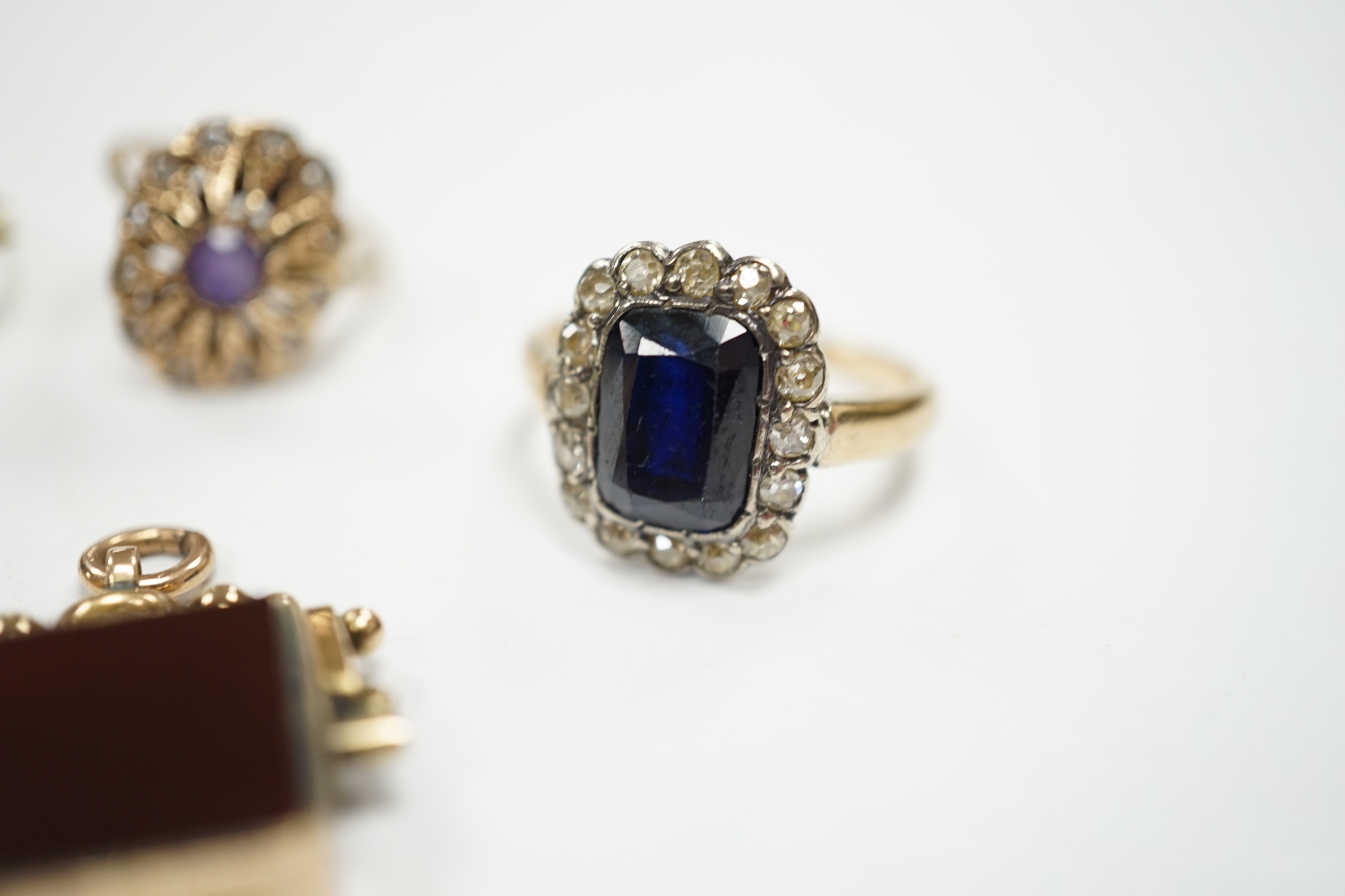 A 750 yellow metal, single stone sapphire and three stone diamond set crossover ring, size, three other yellow metal and gem set rings including a continental 875 white metal and 585 yellow metal, synthetic sapphire or s